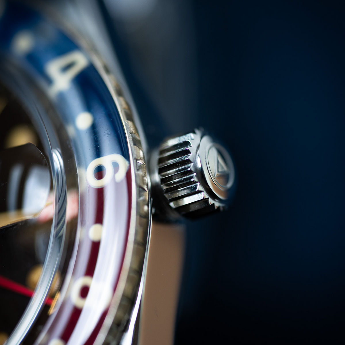 Extreme close-up of WMT Panton MKII - Brown Dial/ Heavy Aged watch side detail, showing the blue-red dial bezel and crown