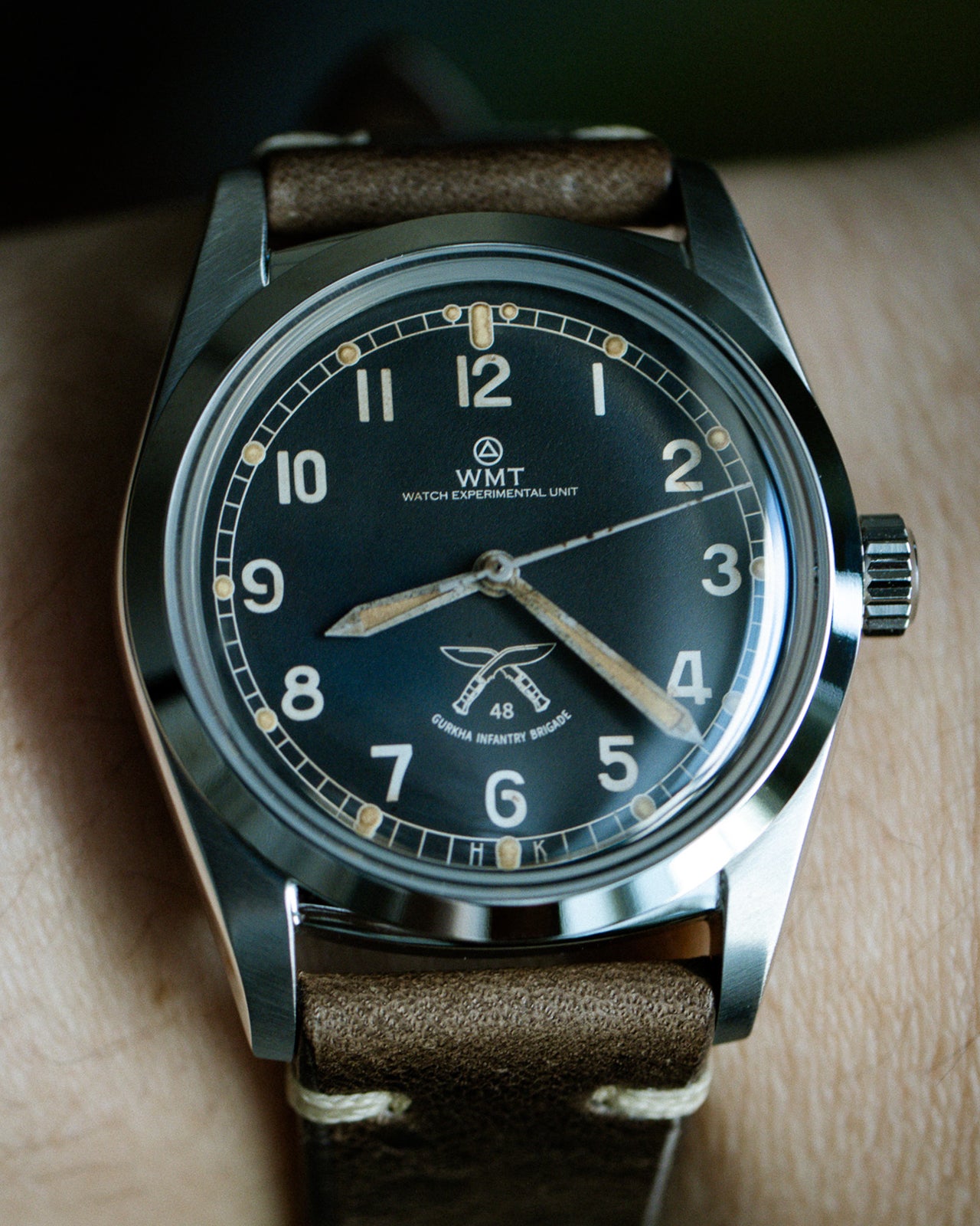 Wristwatch with brown leather strap and black dial on a wrist