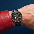 Wrist shot of AVI-8 Snoopy watch with a black dial, silver-toned case, and black leather strap