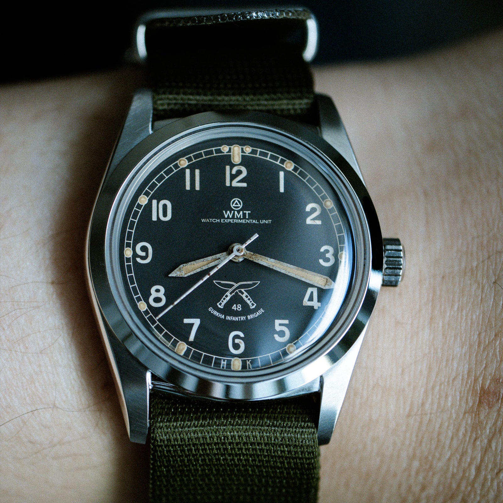Wristwatch with green strap and black dial on a wooden surface