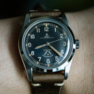 Wristwatch with brown leather strap and black dial on a wrist