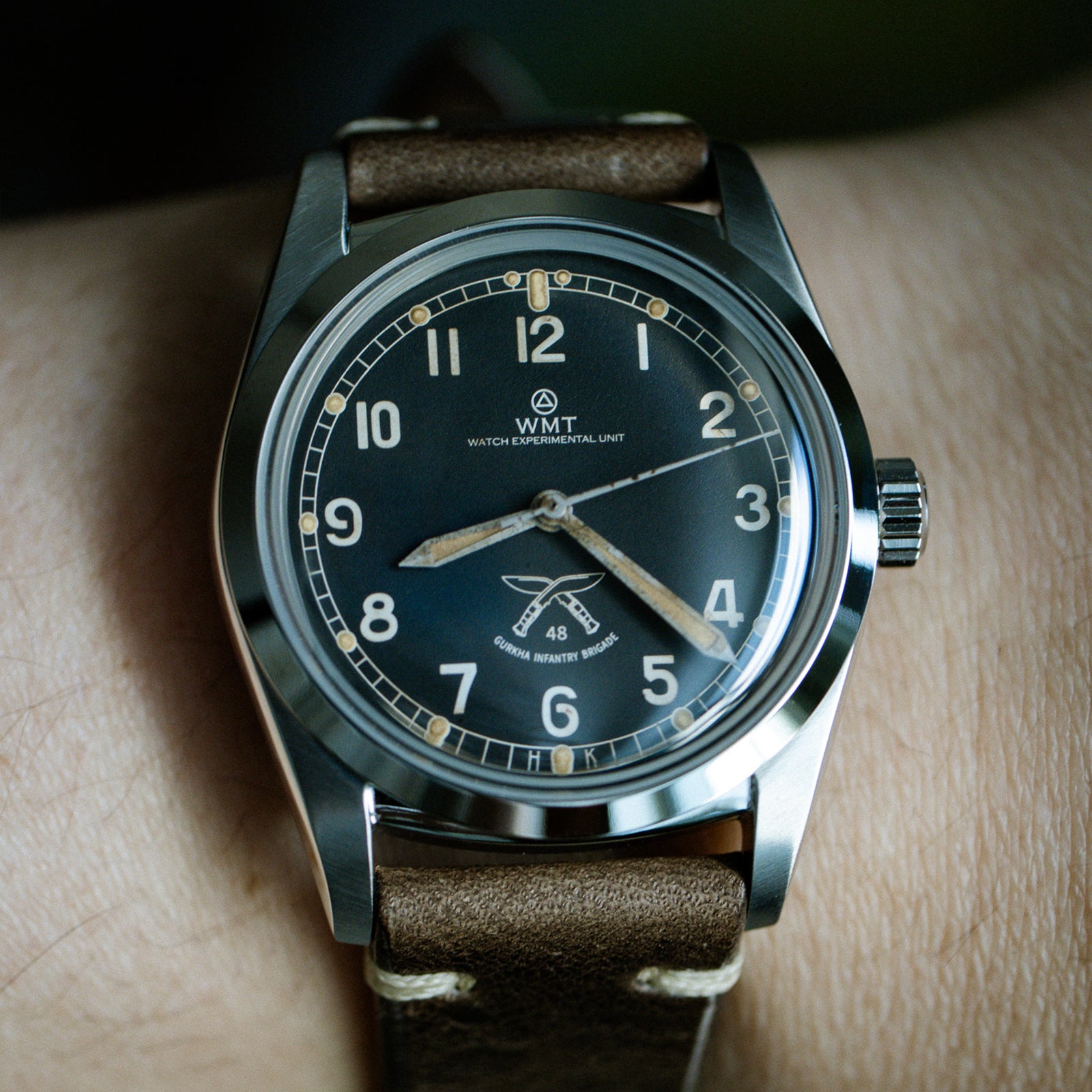 Wristwatch with brown leather strap and black dial on a wrist